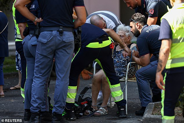 Emergency servicies personnel help an elderly woman near the scene where a gas station exploded on the outskirts of Rome, Italy, July 4, 2025