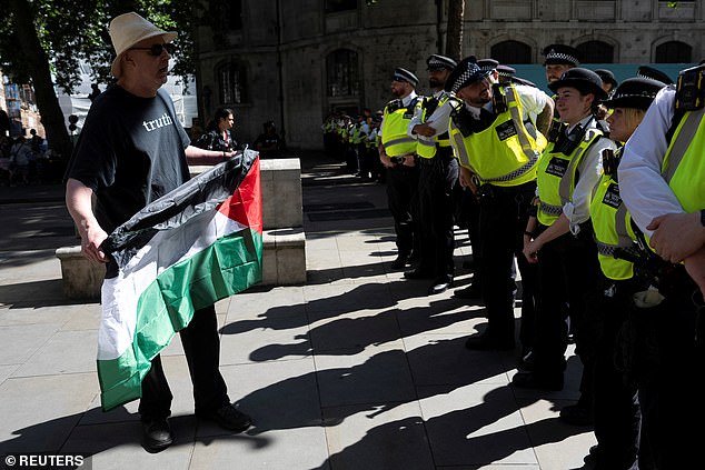 A supporter of pro-Palestinian campaign holding a Palestinian flag in-front of the police outside London's High Court in London