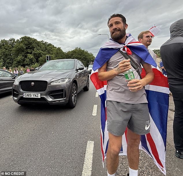 One bearded man wearing shorts draped a union flag over his shoulders as he took selfie pictures outside the embattled hostel