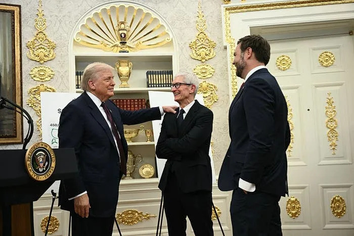 Three men in suits chat and smile in an ornate room with presidential decor