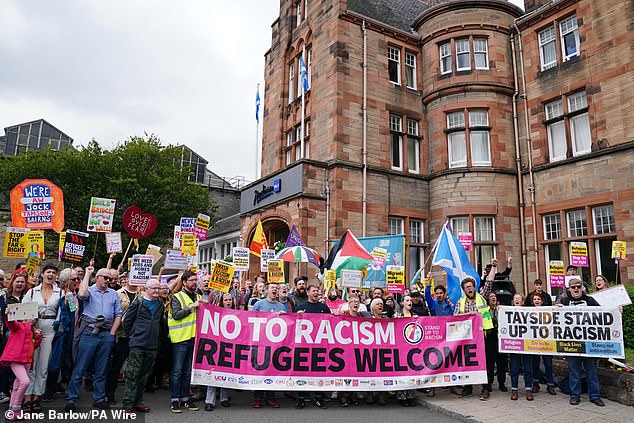 A large group of counter protesters pose for photos as they hold a banner reading 'No to racism, refugees welcome' in Perth on Saturday