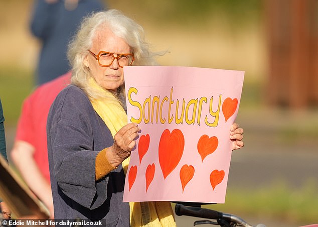 A counter demonstrator holds  a sign which reads, 'sanctuary' with several red hearts