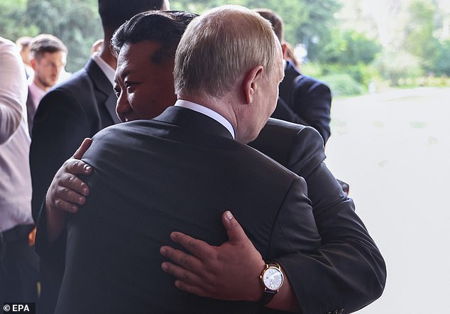 Russian President Vladimir Putin (back) bids farewell to North Korean leader Kim Jong Un following their meeting at the Diaoyutai State Guesthouse