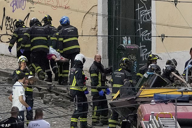 Firefighters carrying the body of a person on a stretcher at the site of a derailed electric streetcar in Lisbon, Portugal