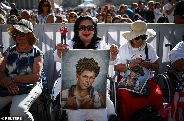 A woman holds a figure and a tapestry depicting Carlo Acutis on the day Pope Leo XIV leads a Holy Mass for the canonisation of the 15-year-old, in St. Peter's Square at the Vatican