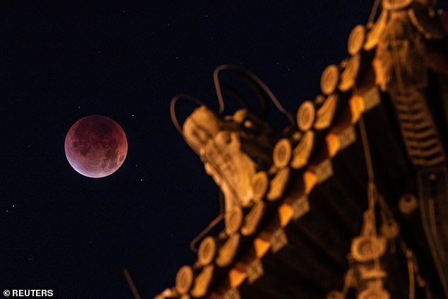 The 'Blood Moon' is seen over the roof of Yongdingmen Gate on the night of a total lunar eclipse in Beijing, China