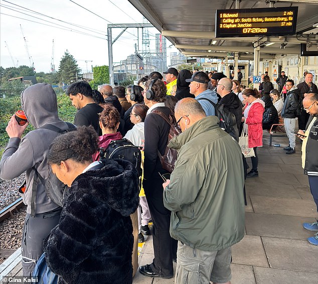 Passengers wait for a London Overground Mildmay line train at Willesden Junction today