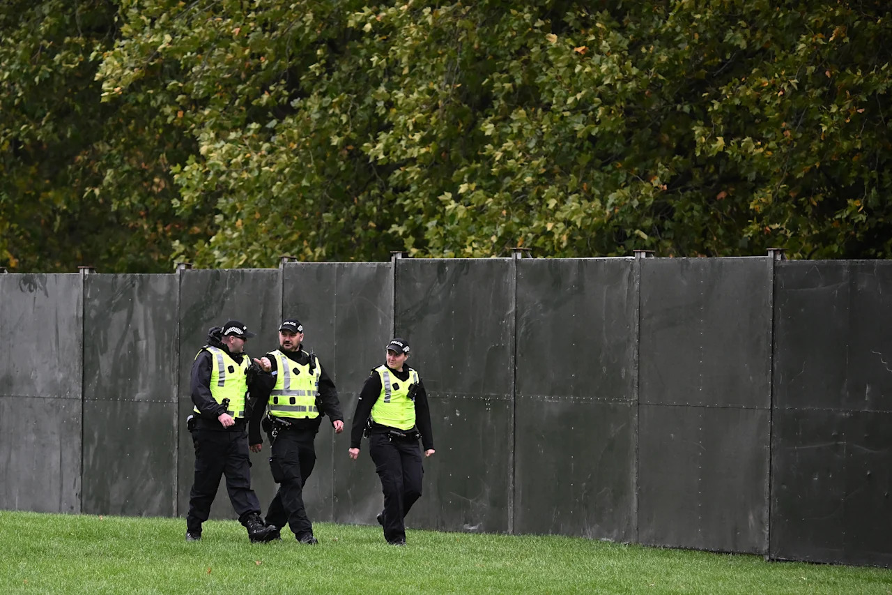 Police officers patrol a temporary fence, blocking off the Long Walk in the grounds of Windsor Castle, in Windsor, on September 17, 2025, during US President Donald Trump's second State Visit to the UK. US President Donald Trump arrived in Britain on Tuesday for an unprecedented second state visit, with the UK government rolling out a royal red carpet welcome to win over the mercurial leader. (Photo by Paul ELLIS / AFP) (Photo by PAUL ELLIS/AFP via Getty Images)          