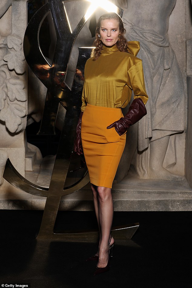 Eva Herzigová flaunted her curves in a mustard yellow satin blouse, teamed with a matching skirt and burgundy leather gloves