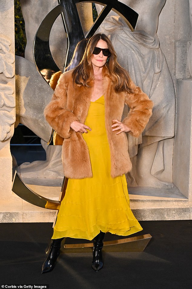 The former First Lady was seen wearing a mustard dress with a brown fur coat. The contrast between her appearance at the show and the gravity of the charges surrounding her family was striking
