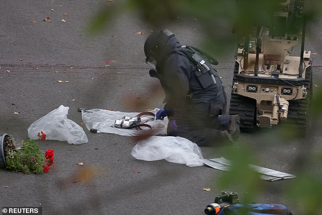 A bomb disposal expert from the British Army's 11 Explosive Ordnance Disposal and Search Regiment is seen investigating the device worn by the terrorist