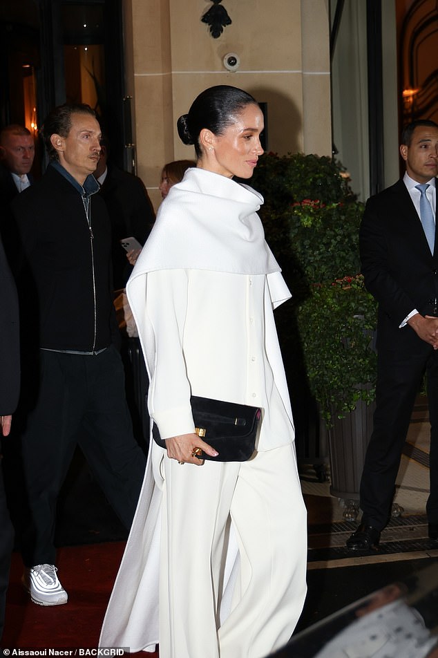 She was snapped wearing a stylish white oversized cape over a white button-down shirt with matching trousers
