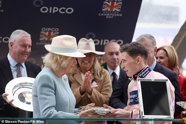 Queen Camilla presents jockey Jason Watson with a trophy after winning the Queen Elizabeth II Stakes at Ascot Racecourse, Berkshire. Picture date: Saturday October 18, 2025