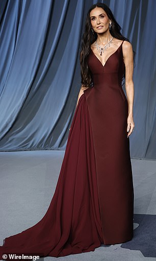 Demi Moore stunned in a fitted dark red dress that contained flowy material on the right side for a unique flare