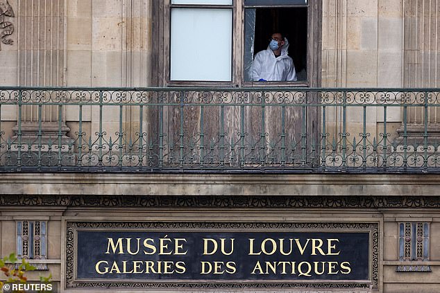 A member of a forensic team inspects a window believed to have been used in what the French Interior Ministry said was a robbery at the Louvre museum