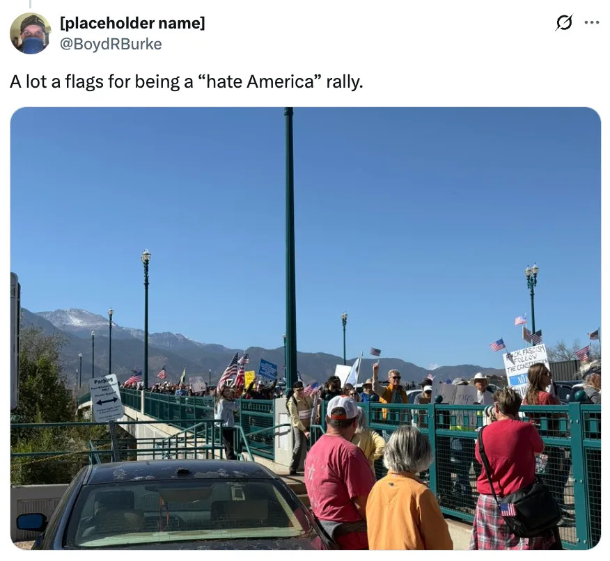 Crowd with protest signs and flags gathered on a bridge during a rally