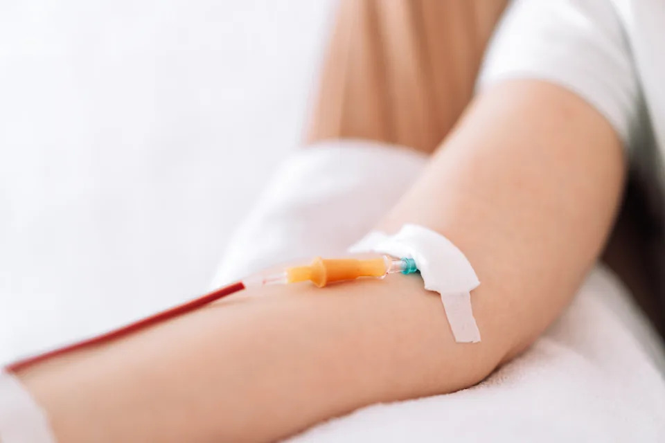 A person receiving an intravenous (IV) injection in their arm, depicting a medical procedure