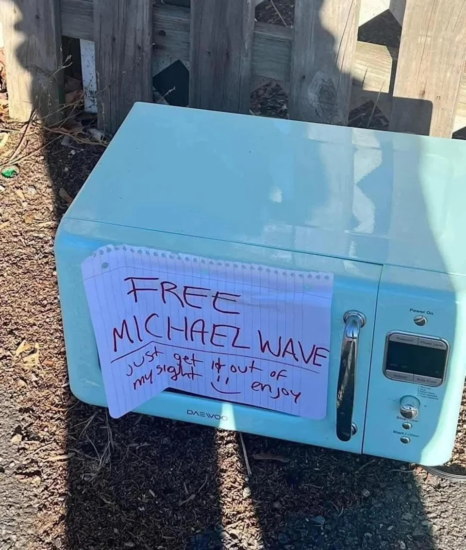 A microwave with a handwritten sign saying, "FREE MICHAEL WAVE, just get it out of my sight!! enjoy."