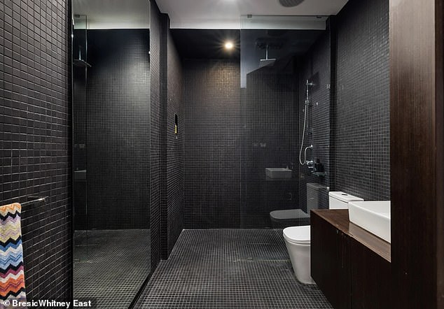 The mosaic-tiled bathroom framed in glass is one of the moodiest features