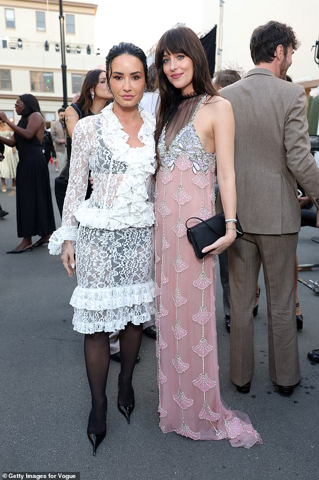 Joining a string of big names at the runway show, Dakota posed with singer Demi Lovato, 33, who looked chic in a white lace dress with a ruffled collar