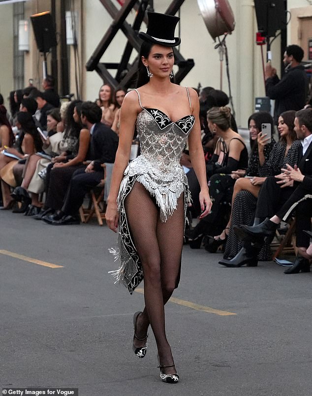 Jenner donned the sparkling silver, corset bodysuit with tasseled details and fabric that fell down behind her