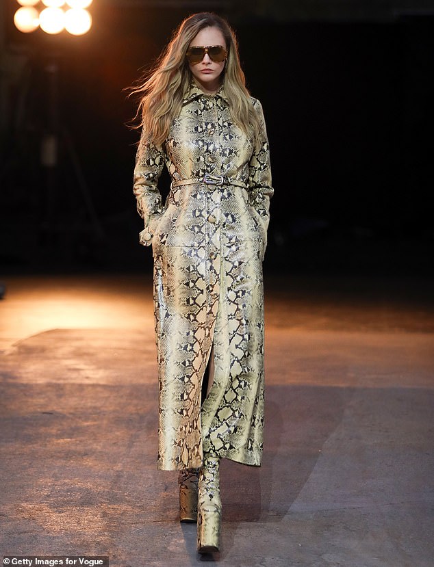 Cara Delevingne could be seen wearing a snakeskin coat that was secured with a belt around her midriff and also donned a pair of matching platform boots