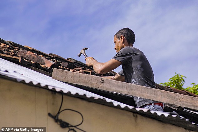 A man hammers the roof of his home ahead of the arrival of Hurricane Melissa on October 27, 2025