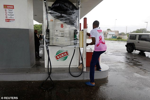 A man wraps a petrol pump as Hurricane Melissa approaches, Kingston, Jamaica, October 27, 2025