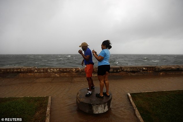 People stand along the Kingston waterfront as Hurricane Melissa approaches, in Kingston, Jamaica, October 27, 2025