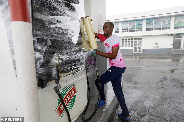 RUBiS Jamaica worker Craig Brown, wraps a gas pump, as Hurricane Melissa approaches, in Kingston, Jamaica, October 27, 2025.  REUTERS/Octavio Jones