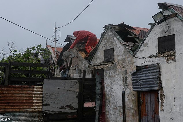 Men remove a loose section of roof in Kingston, Jamaica, as Hurricane Melissa approaches, Tuesday, Oct. 28, 2025. (AP Photo/Matias Delacroix)