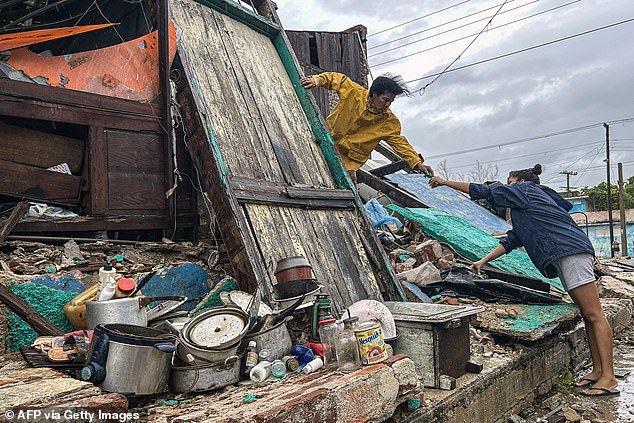 A family salvages belongings from the rubble of their home after it collapsed during Hurricane Melissa's passage through Santiago de Cuba, Cuba, on October 29, 2025. A powerful Hurricane Melissa made landfall in eastern Cuba on Wednesday, causing damage and flooding to homes and streets in Santiago de Cuba province, an AFP team on the ground reported. (Photo by YAMIL LAGE / AFP) (Photo by YAMIL LAGE/AFP via Getty Images)