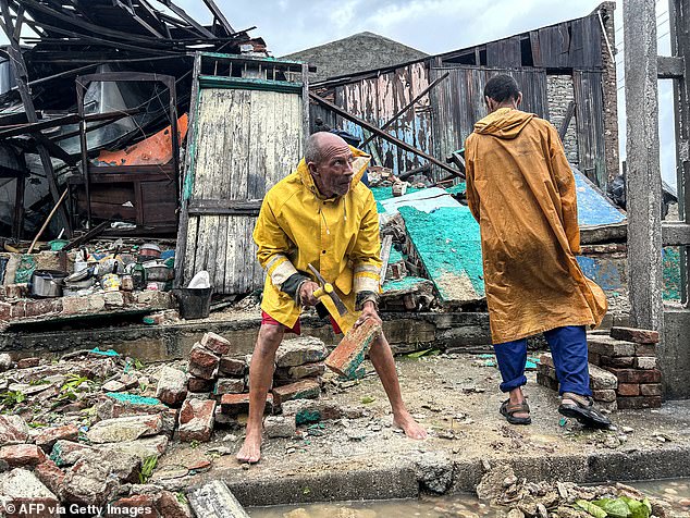 A family salvages belongings from the rubble of their home after it collapsed during Hurricane Melissa's passage through Santiago de Cuba, Cuba, on October 29, 2025. A powerful Hurricane Melissa made landfall in eastern Cuba on Wednesday, causing damage and flooding to homes and streets in Santiago de Cuba province, an AFP team on the ground reported. (Photo by YAMIL LAGE / AFP) (Photo by YAMIL LAGE/AFP via Getty Images)