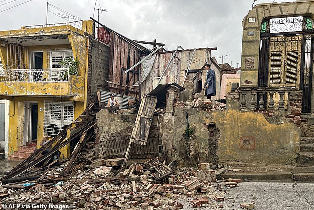 TOPSHOT - Men salvage belongings from the rubble of her their home after it collapsed during Hurricane Melissa's passage through Santiago de Cuba, Cuba, on October 29, 2025. A powerful Hurricane Melissa made landfall in eastern Cuba on Wednesday, causing damage and flooding to homes and streets in Santiago de Cuba province, an AFP team on the ground reported. (Photo by Yamil LAGE / AFP) (Photo by YAMIL LAGE/AFP via Getty Images)