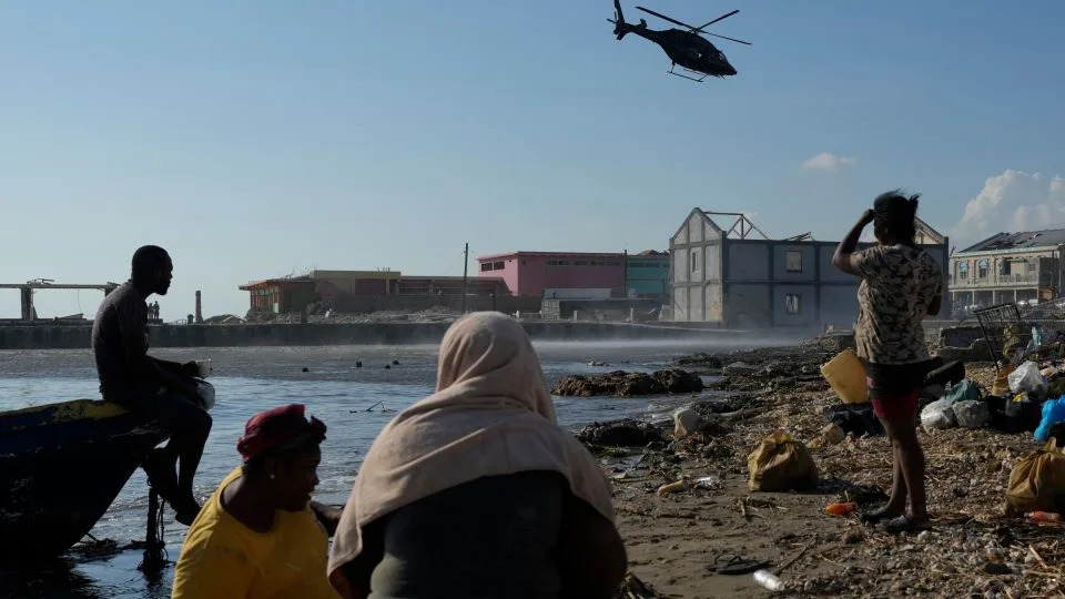 Residents watch a helicopter depart after dropping off medical supplies in Black River, Jamaica, on Thursday. - Matias Delacroix/AP