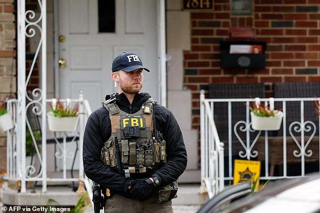 An FBI agent stands guard outside a home in Dearborn