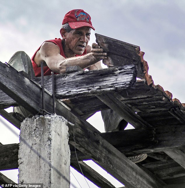 A man attempts to secure the roof of his home ahead of the arrival of Hurricane Melissa on October 27, 2025