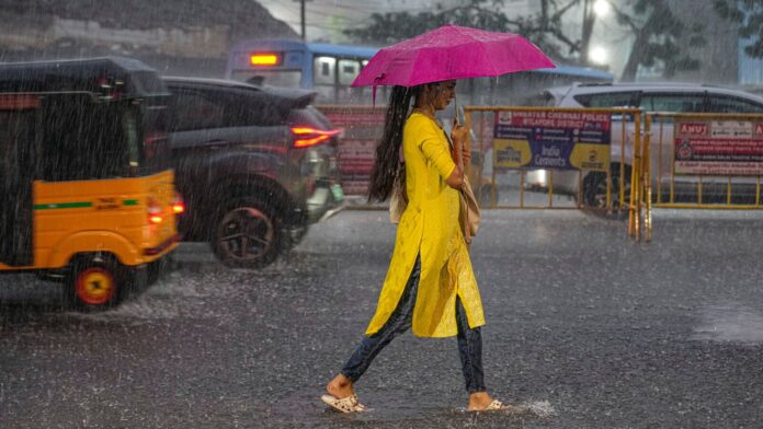 Chennai: A woman walks with an umbrella on a road during heavy rainfall, in Chennai.