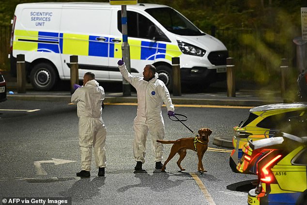 A white-suited forensic officer at car park of Huntingdon station after 10 were hospitalised in a knife rampage on a train