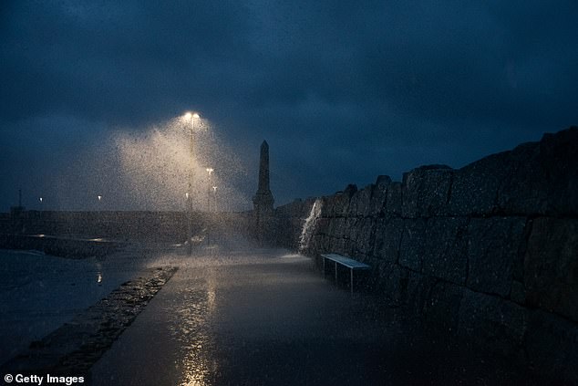 Waves crash overDun Laoghaire Pier during a storm squall on October 14, 2025