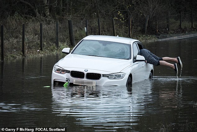 A stranded motorist in a flood on a country road near Twechar in East Dunbartonshire