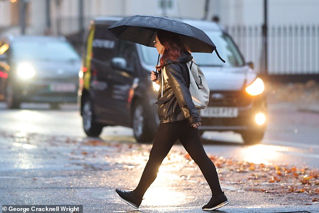 A commuter uses an umbrella during heavy rain near Euston station in London yesterday