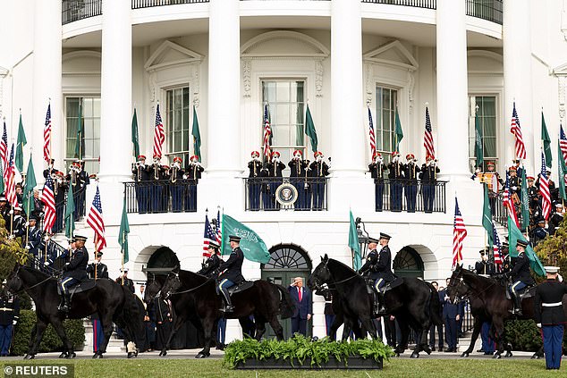 A procession of cavalry bearing the green Saudi flag outside the White House