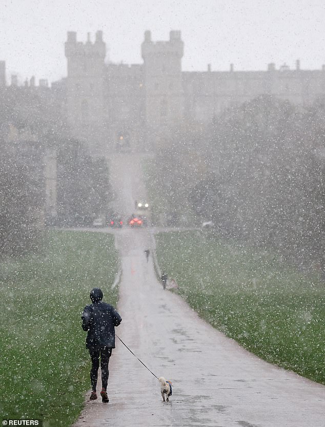 A person runs as snow begins to fall near Windsor Castle in Berkshire this morning