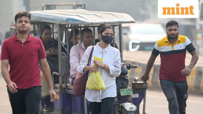 Delhi-NCR breathes ‘very poor’ air as AQI touches 391; CAQM Commuters wear masks to protect themselves from pollution.